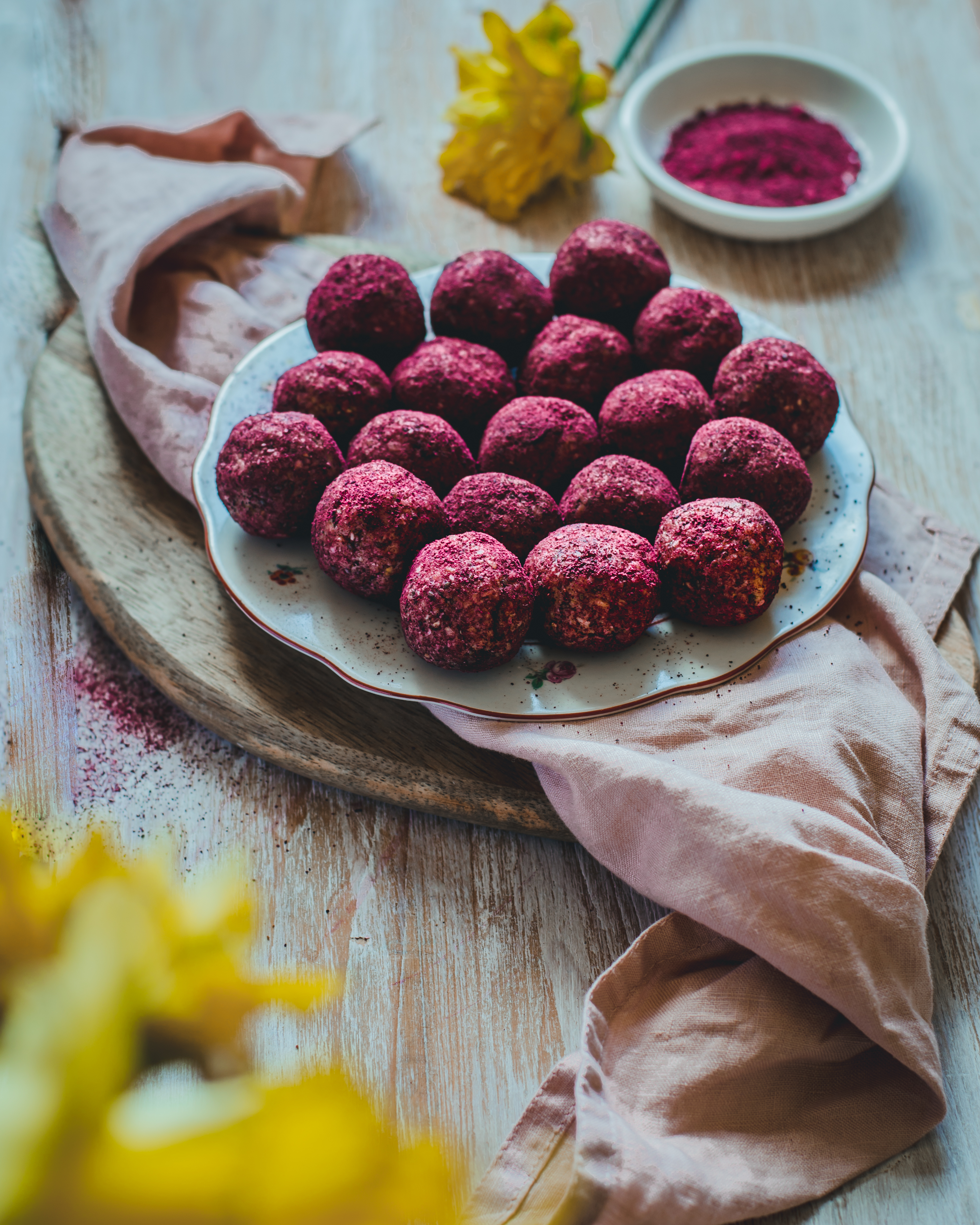 energy bliss balls on a plate covered in raw beetroot powder